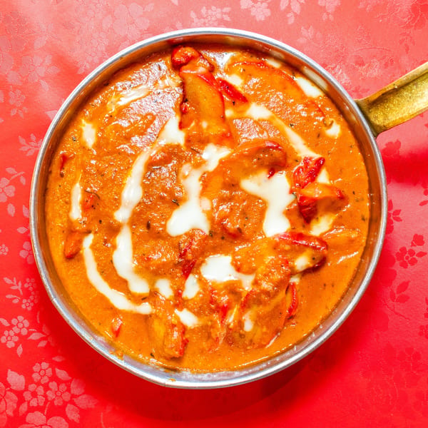 Delhi Diner's chicken tikka masala, a creamy orange curry with white swirls, in a metal pan.