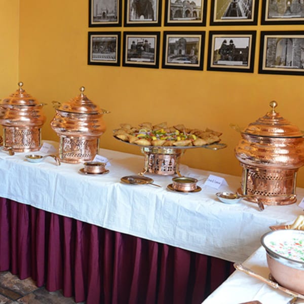 A buffet table at Delhi Diner with Indian food, including samosas and copper chafing dishes.