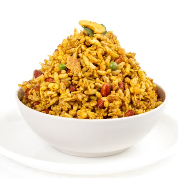 A white bowl filled with Delhi Diner's Indian snack mix, Bhel Puri, on a white background.