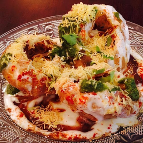 Delhi Diner's Indian chaat, a savory snack with yogurt, chutneys, and crispy toppings on a clear plate.