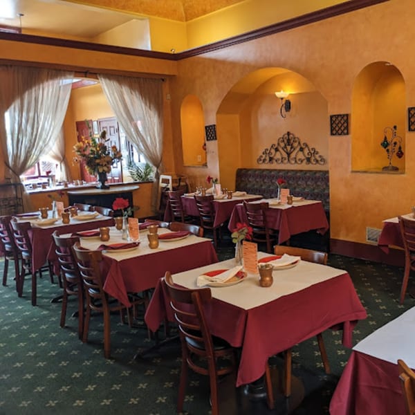 The Delhi Diner dining room features warm orange walls, arched alcoves, and tables with red and white tablecloths.