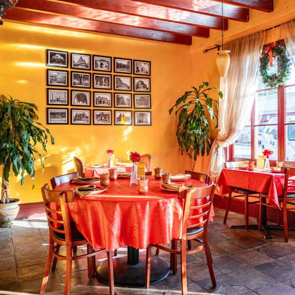 Delhi Diner's dining room with yellow walls, red tables, and framed Indian landmark photos.