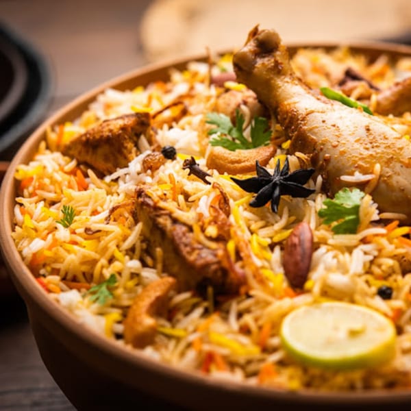 Chicken Biryani from Delhi Diner, garnished with spices, cashews, and a lime slice.